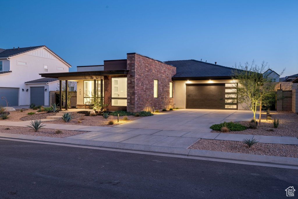 Contemporary home featuring a garage, stucco siding, driveway, and stone siding