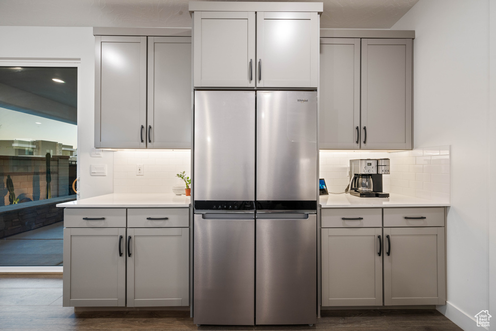 Kitchen featuring freestanding refrigerator, dark wood finished floors, backsplash, and gray cabinetry