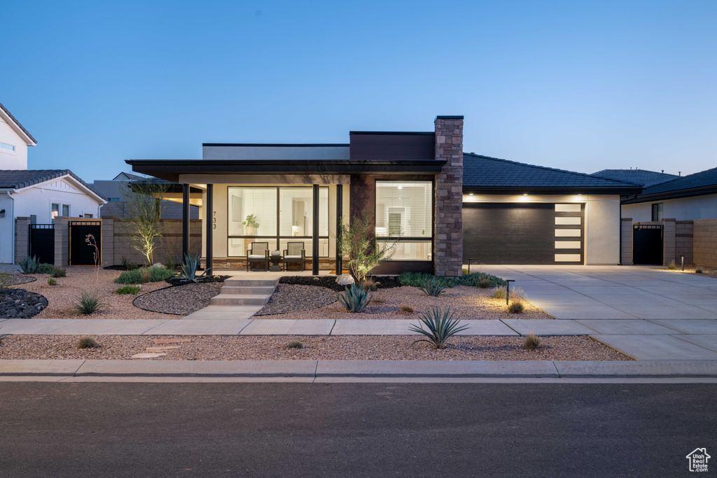 Modern home featuring fence, a garage, a gate, covered porch, and driveway