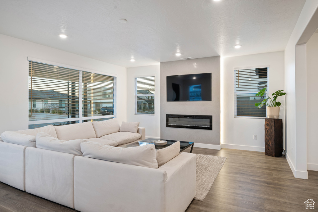 Living room with a glass covered fireplace, baseboards, recessed lighting, and wood finished floors