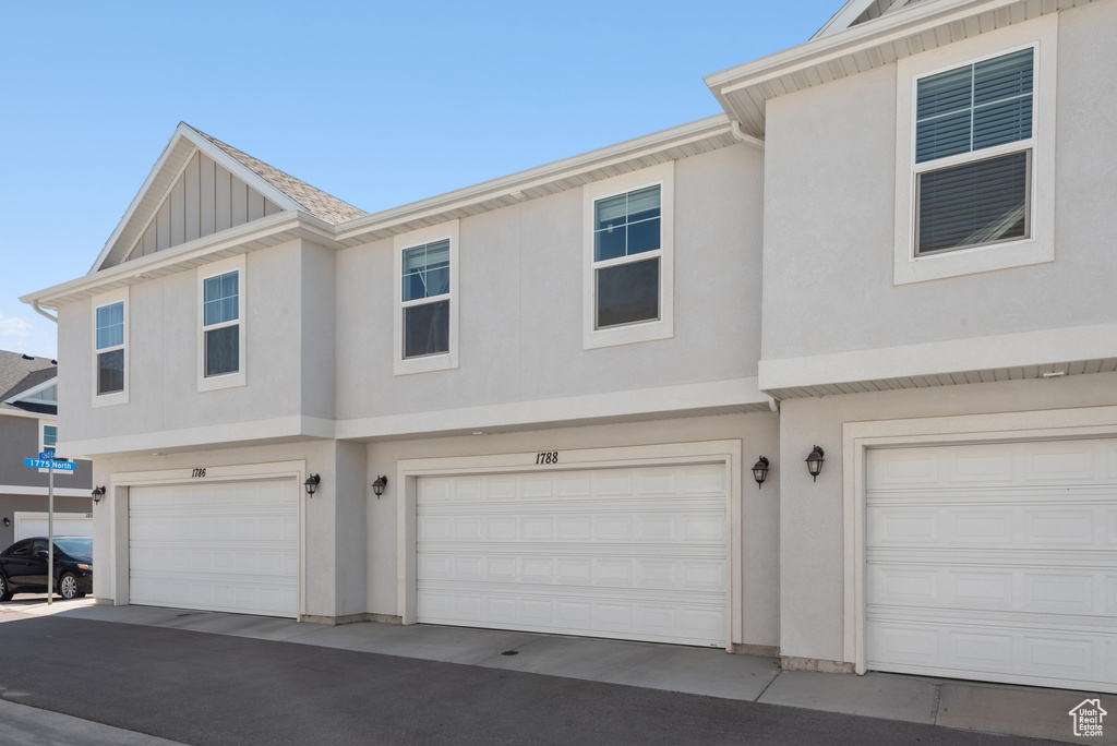 View of front facade with board and batten siding, an attached garage, and stucco siding
