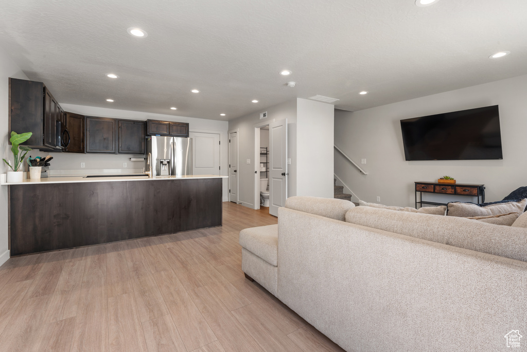 Living area with stairway, baseboards, light wood-style floors, and recessed lighting