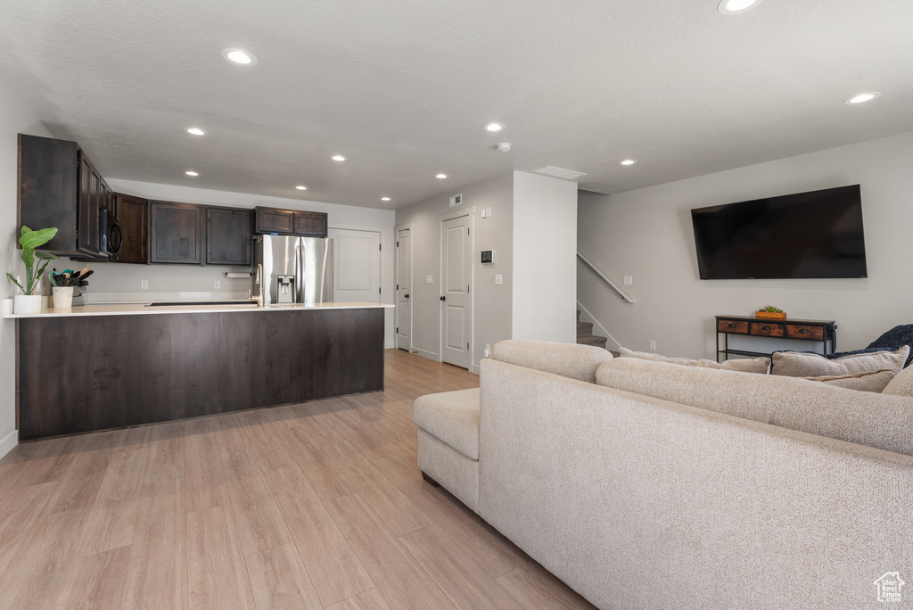 Living area with stairway, baseboards, recessed lighting, and light wood-style flooring