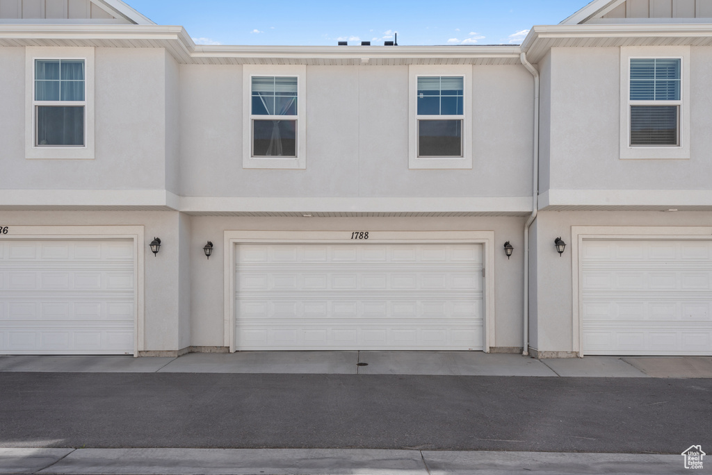 Exterior space featuring a garage, board and batten siding, and stucco siding