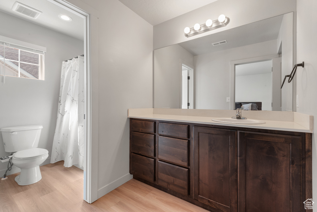 Full bathroom with visible vents, wood finished floors, toilet, and vanity