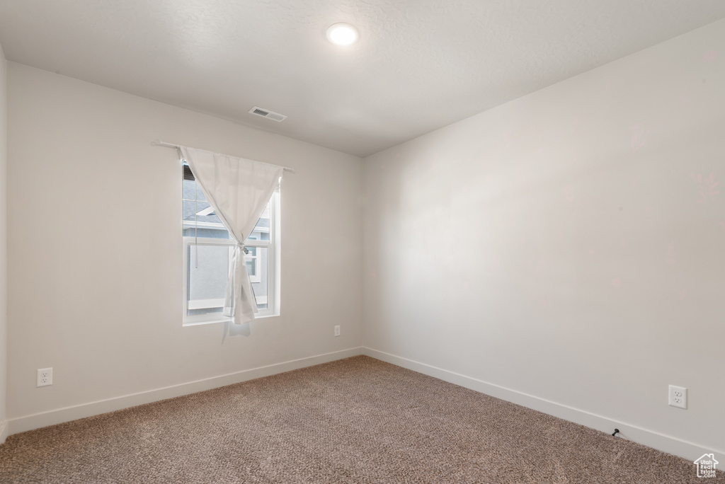 Carpeted empty room featuring baseboards and visible vents