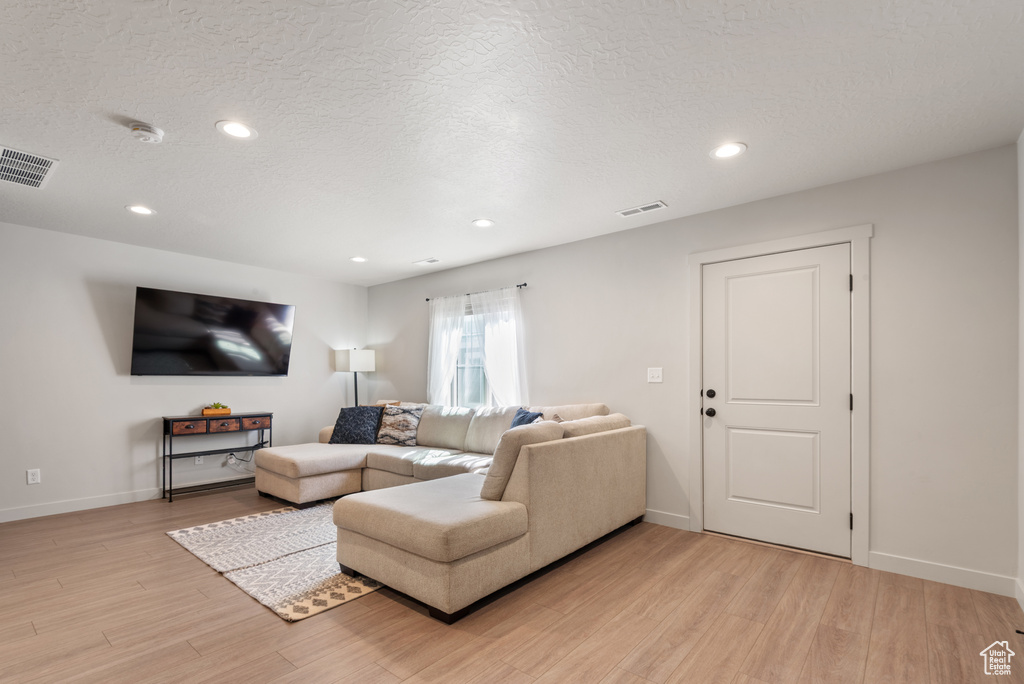 Living room featuring light wood-style floors, baseboards, recessed lighting, and visible vents