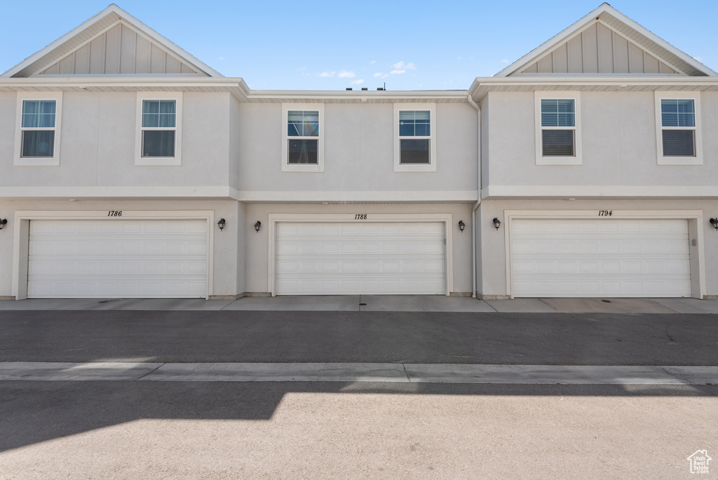 View of front of house with board and batten siding, an attached garage, and stucco siding