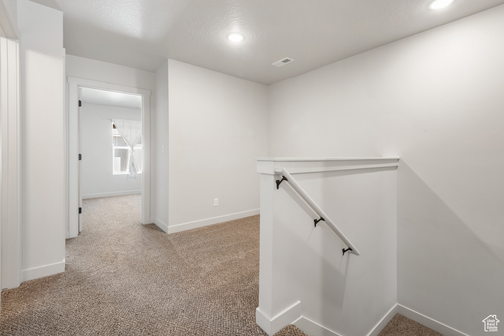 Hall featuring baseboards, light carpet, recessed lighting, and an upstairs landing