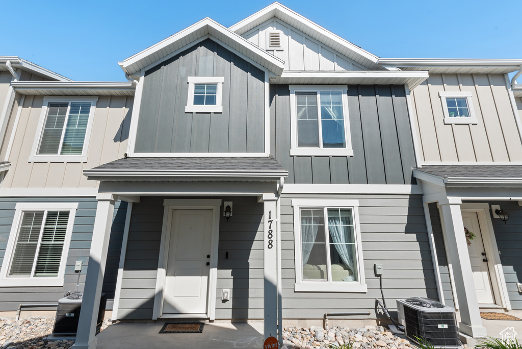 Townhome / multi-family property with a shingled roof, board and batten siding, and central AC