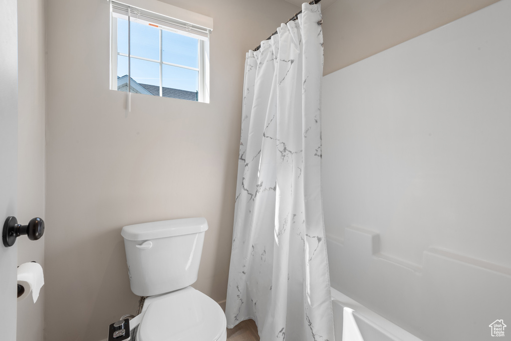 Full bath with a shower with curtain and toilet