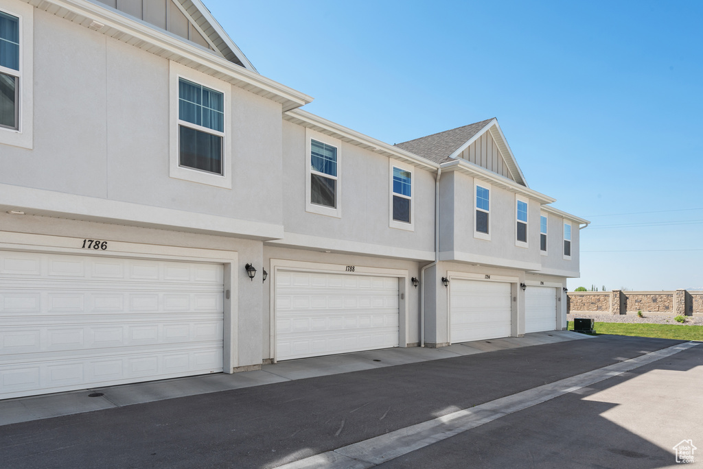 View of side of home featuring board and batten siding, an attached garage, and stucco siding