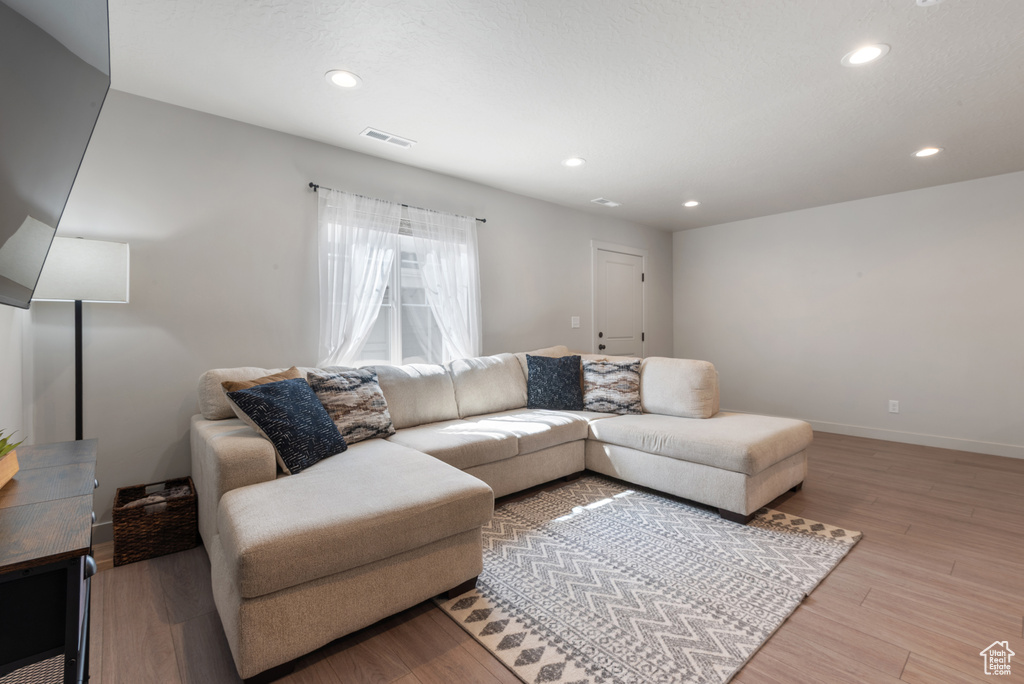 Living room with recessed lighting, baseboards, visible vents, and light wood finished floors
