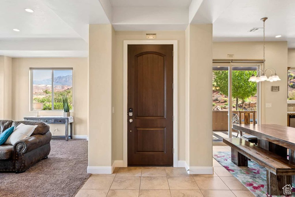 Entryway featuring an inviting chandelier, light tile patterned flooring, baseboards, recessed lighting, and light colored carpet