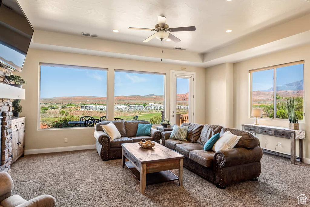 Carpeted living area with a ceiling fan, baseboards, visible vents, and a mountain view