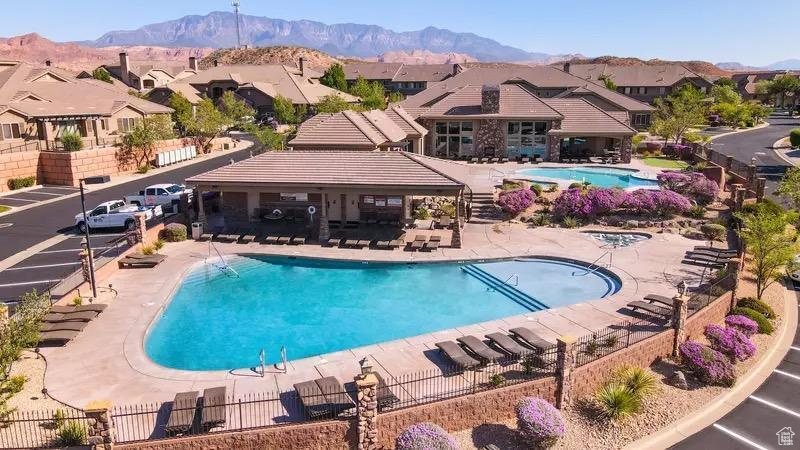 Community pool with a patio area, a mountain view, fence, and a residential view