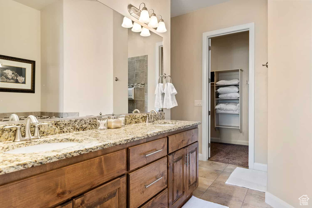 Bathroom featuring tile patterned flooring, a sink, a walk in closet, and double vanity