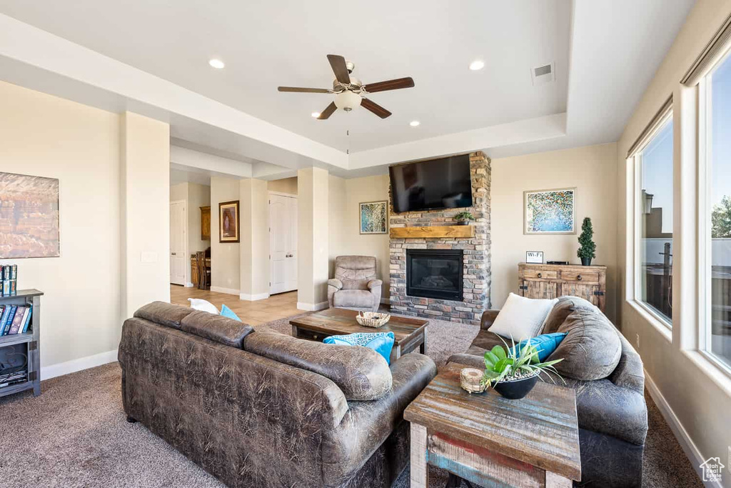 Living area featuring visible vents, a ceiling fan, carpet floors, and a stone fireplace