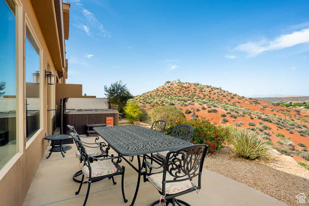 View of patio / terrace featuring a hot tub, a mountain view, and outdoor dining space