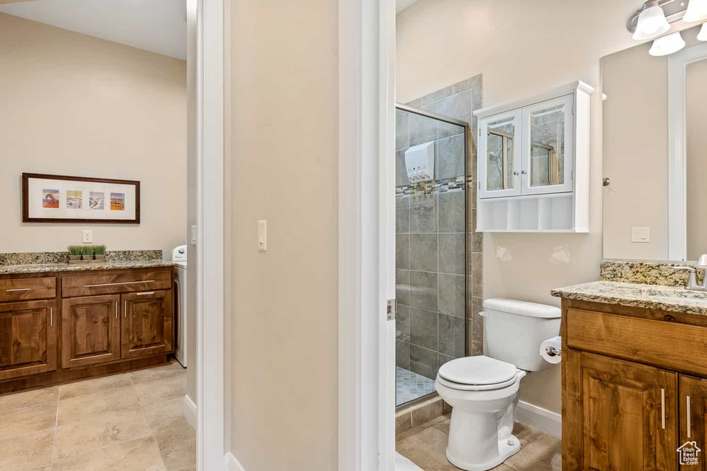 Bathroom with toilet, a shower stall, tile patterned flooring, and vanity