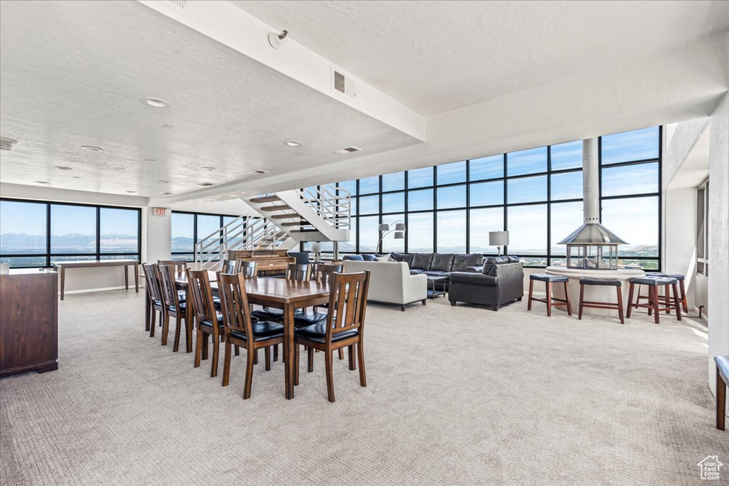 Dining space featuring carpet flooring, a textured ceiling, visible vents, and stairs
