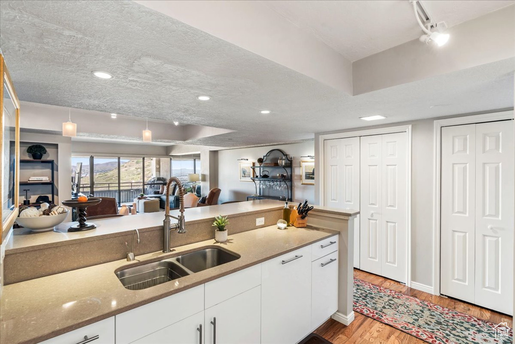 Kitchen featuring white cabinets, light stone counters, a sink, light wood-style floors, and open floor plan