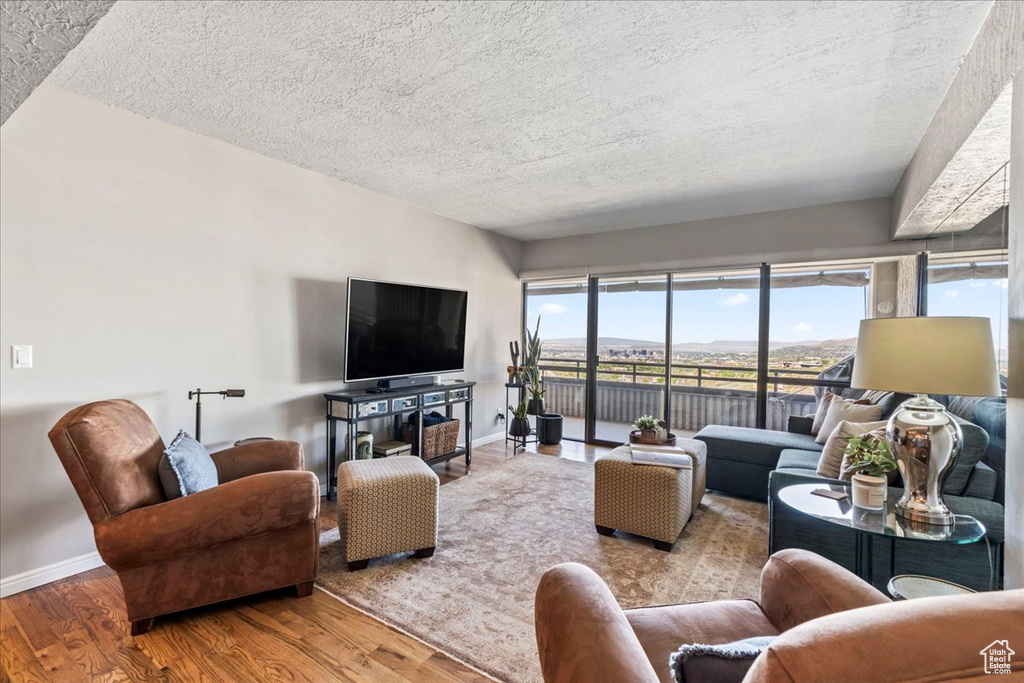 Living area with baseboards, a textured ceiling, and wood finished floors