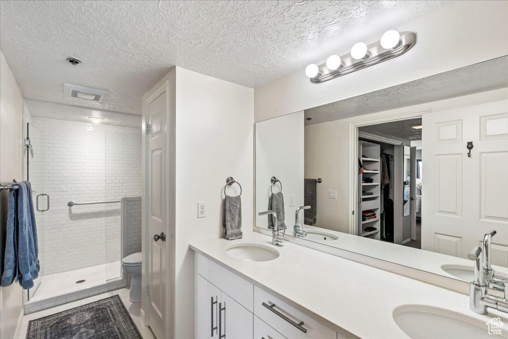 Bathroom with a textured ceiling, a shower stall, and a sink