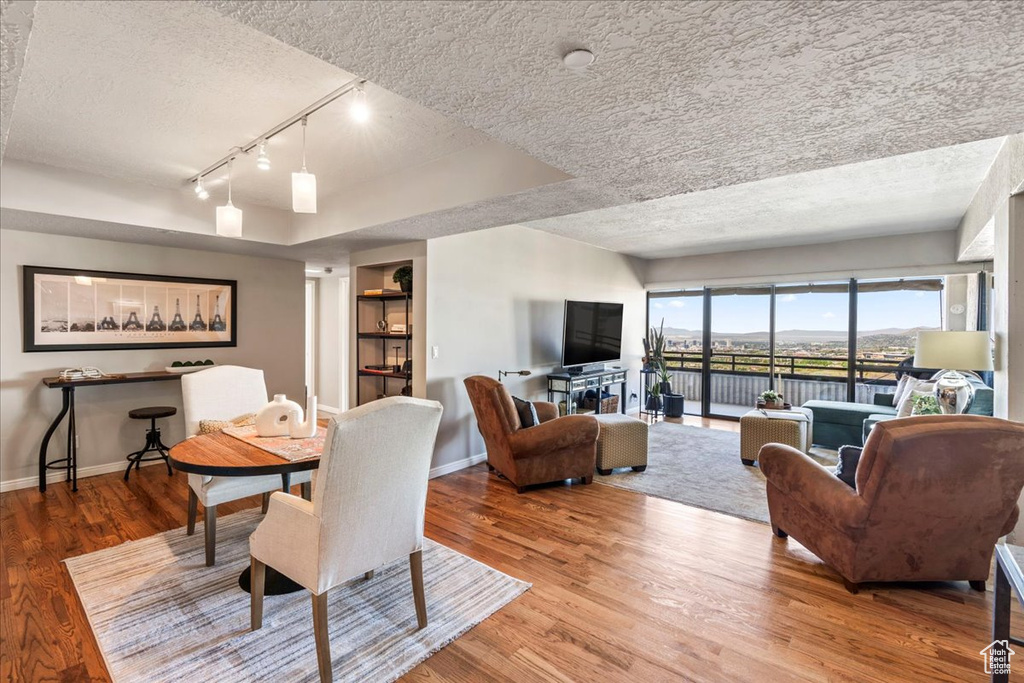 Dining room with baseboards, rail lighting, a textured ceiling, and wood finished floors