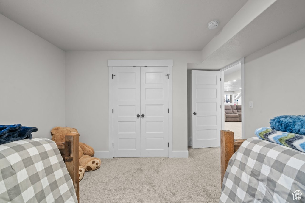 Bedroom featuring baseboards, light colored carpet, and a closet