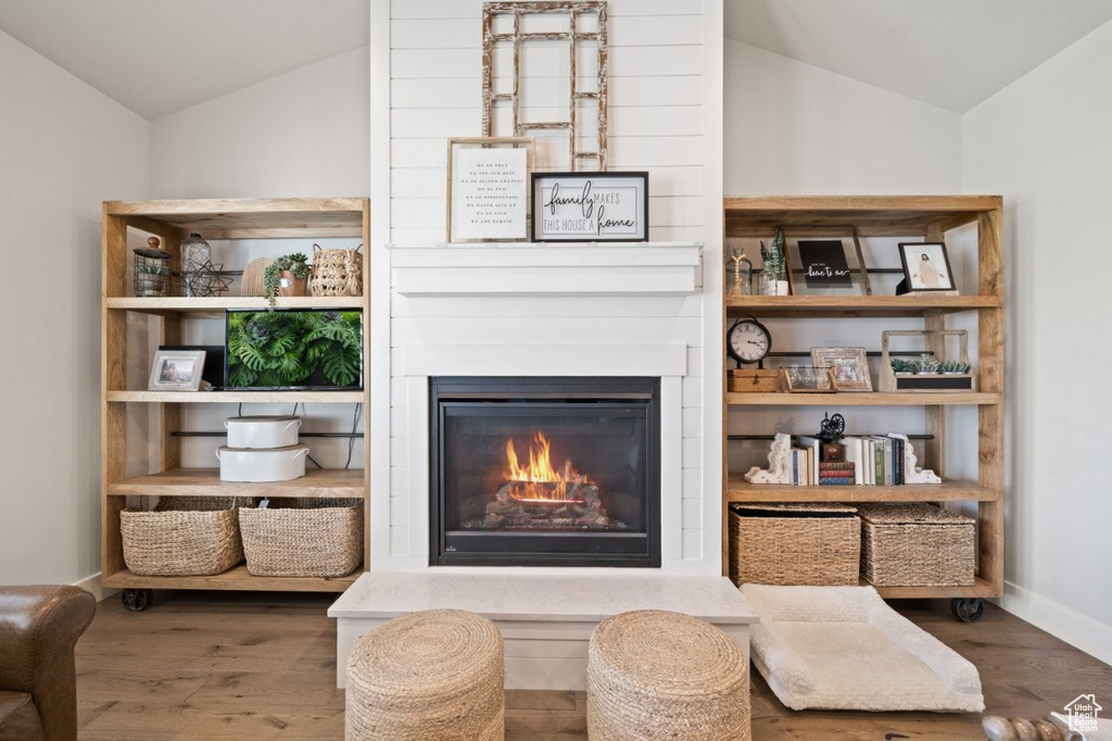 Sitting room featuring a large fireplace, wood finished floors, and lofted ceiling