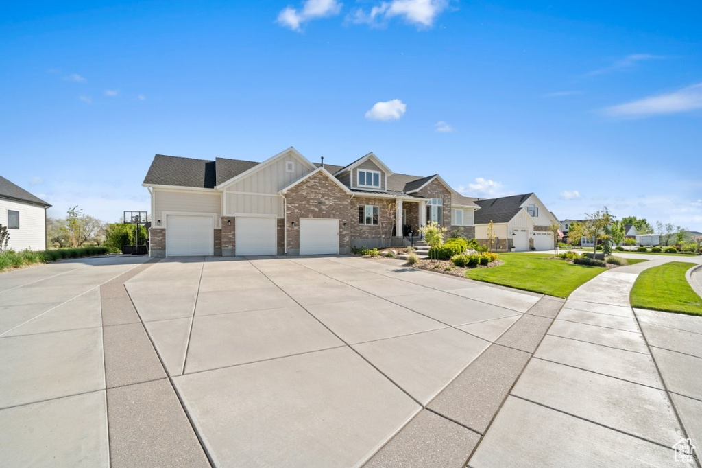 View of front of property featuring a garage, brick siding, board and batten siding, driveway, and a residential view