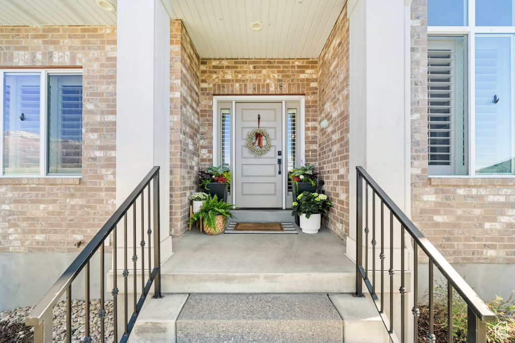 View of exterior entry featuring a porch and brick siding