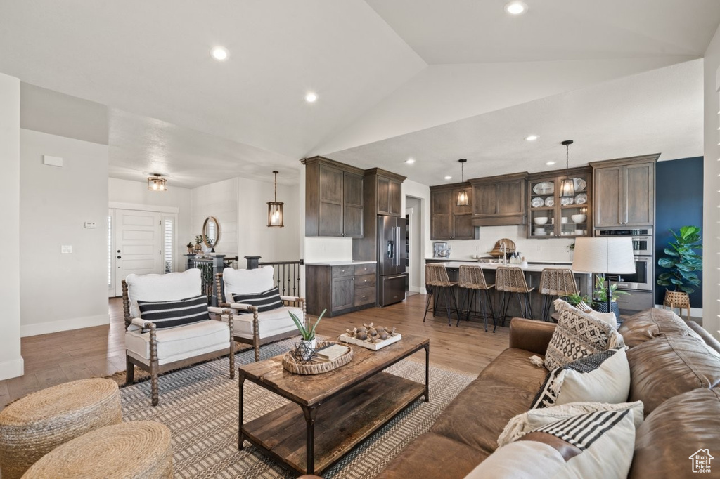 Living room with light wood-style floors, recessed lighting, baseboards, and vaulted ceiling