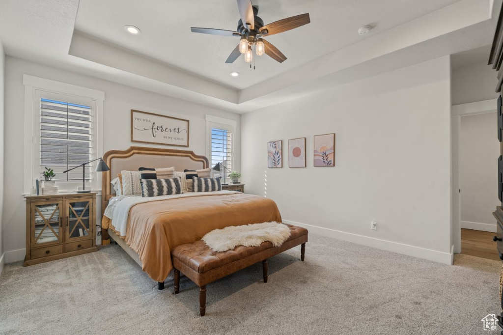 Bedroom featuring light colored carpet, recessed lighting, baseboards, a ceiling fan, and a tray ceiling