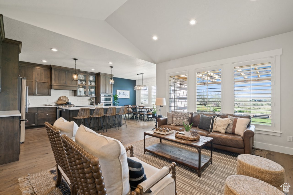 Living room featuring light wood-type flooring, recessed lighting, and lofted ceiling