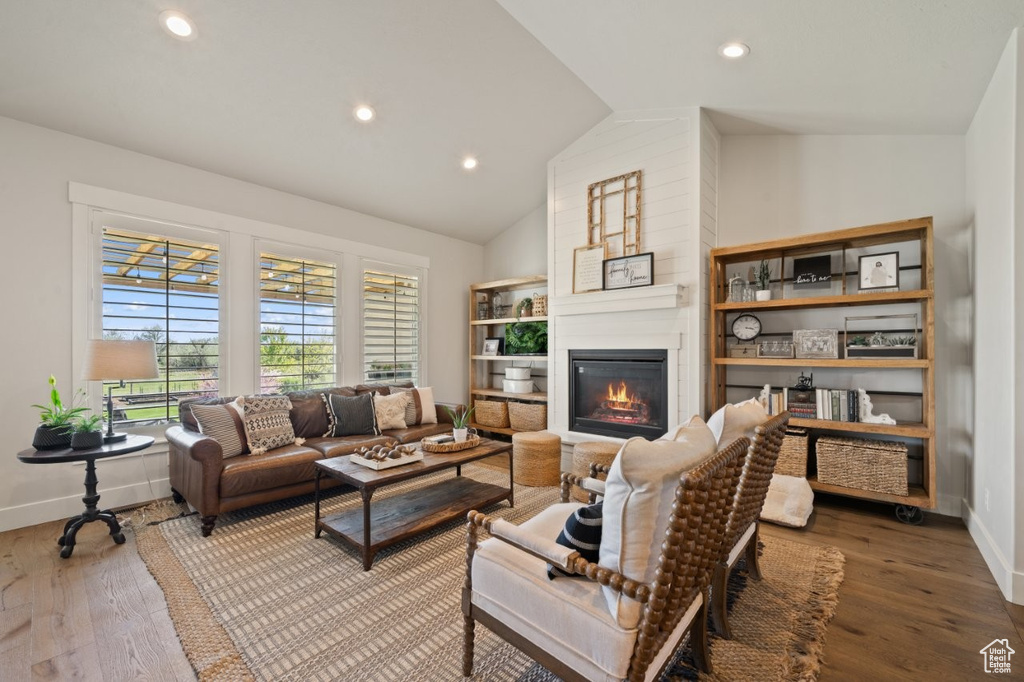 Living area featuring wood finished floors, recessed lighting, lofted ceiling, and a fireplace