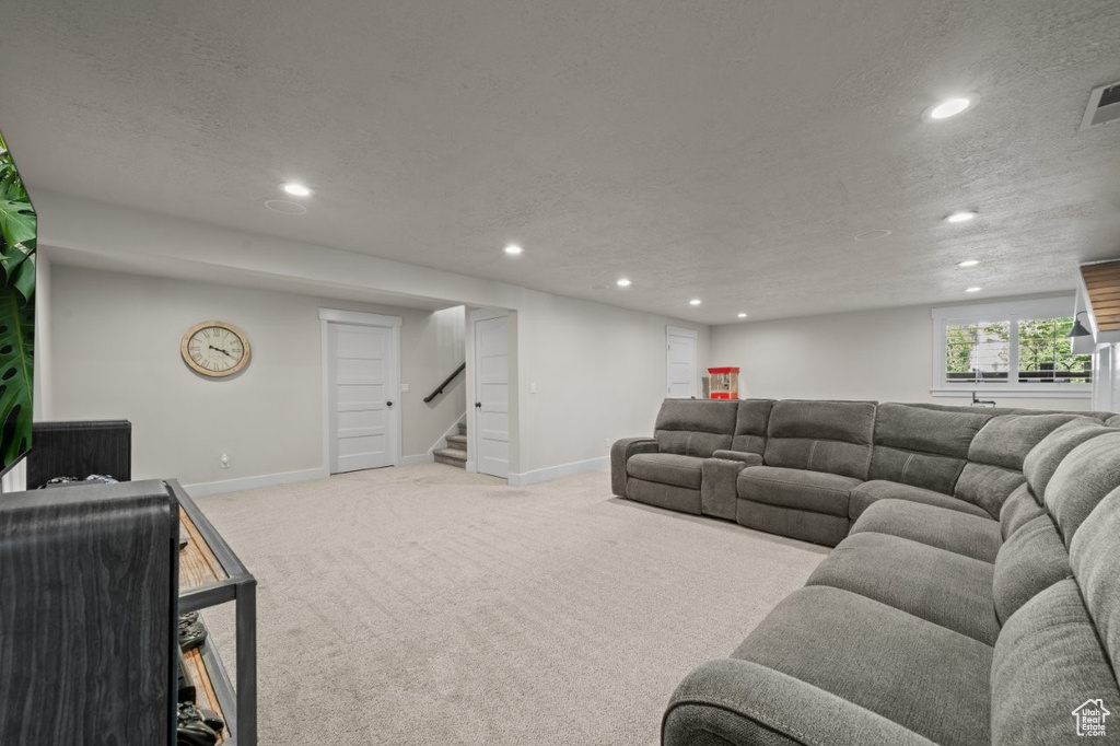 Carpeted living room with recessed lighting, baseboards, and stairway