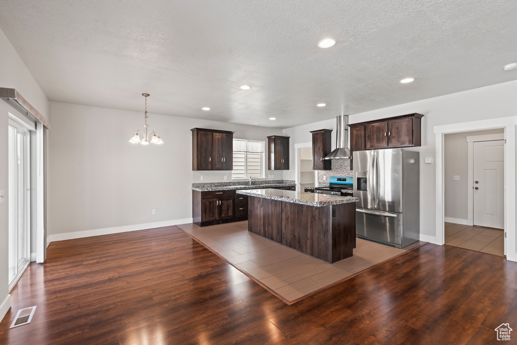 Kitchen with wall chimney range hood, stainless steel appliances, visible vents, and dark brown cabinets