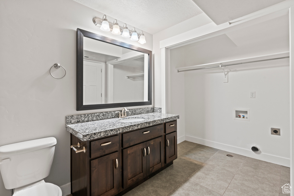 Bathroom with toilet, baseboards, tile patterned flooring, and vanity