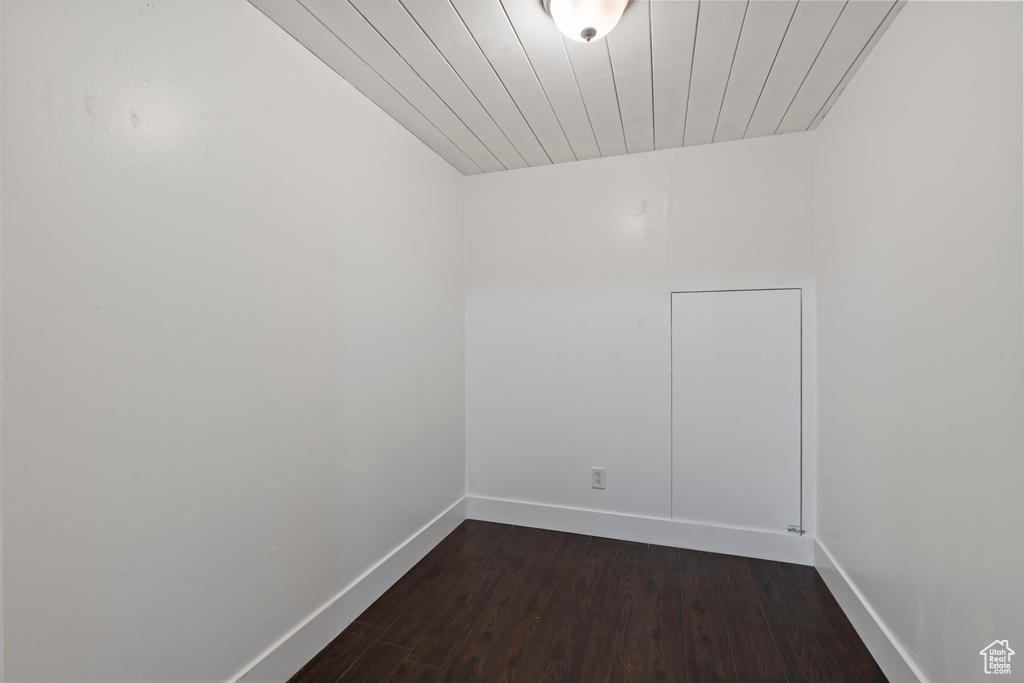 Unfurnished room featuring baseboards, dark wood finished floors, and wooden ceiling