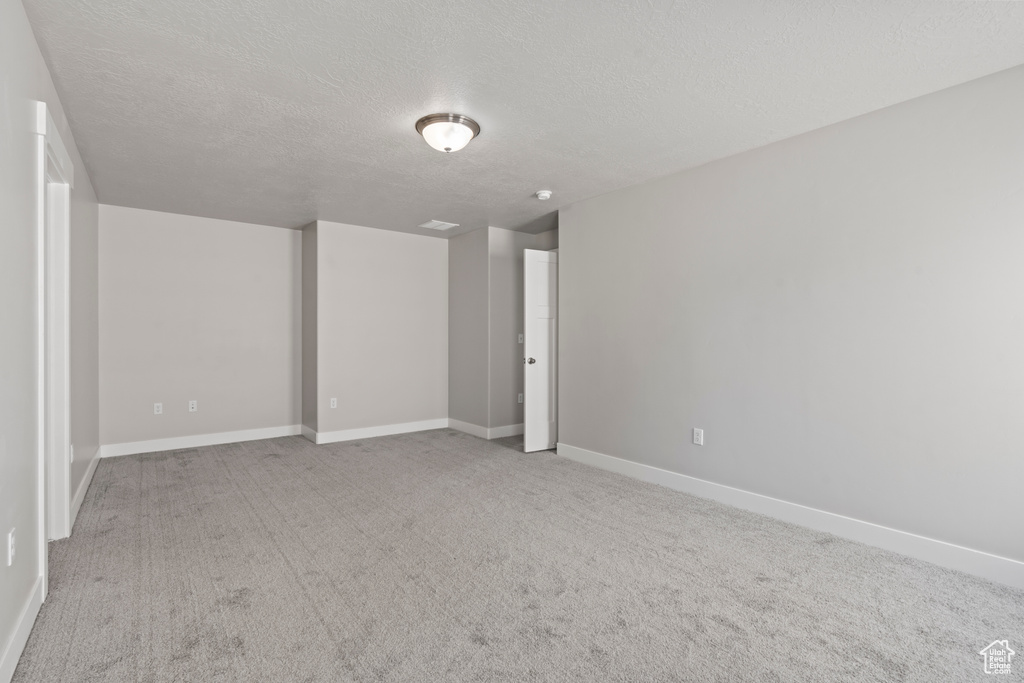 Empty room featuring carpet flooring, a textured ceiling, and baseboards