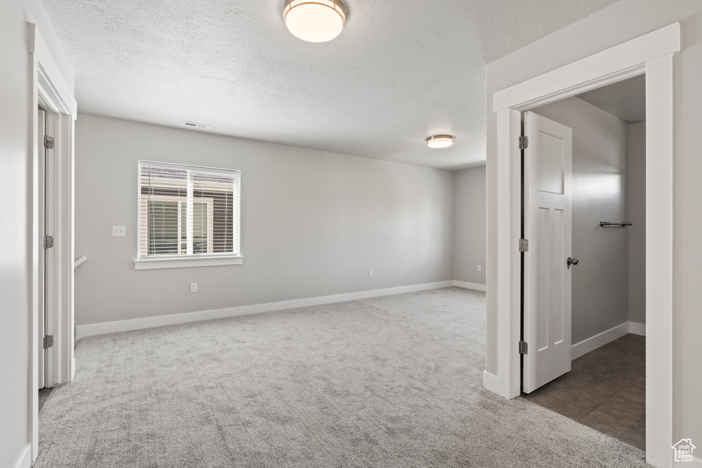 Carpeted spare room featuring baseboards and a textured ceiling