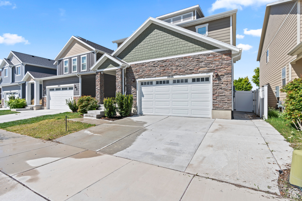 Craftsman-style house featuring a gate, driveway, and stone siding