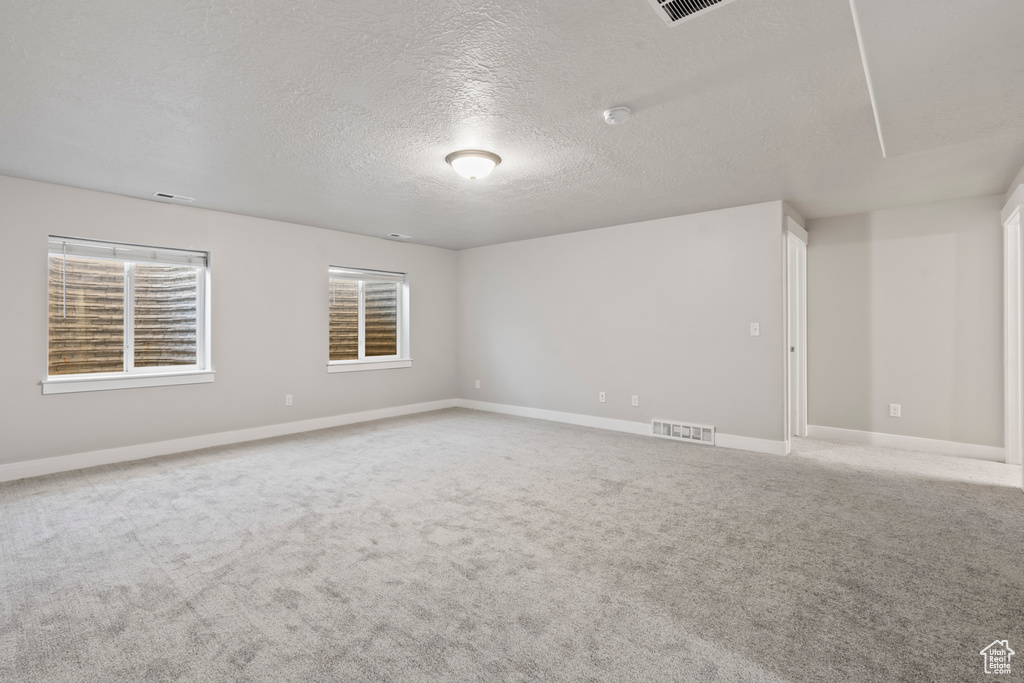 Unfurnished room with visible vents, carpet, a textured ceiling, and baseboards