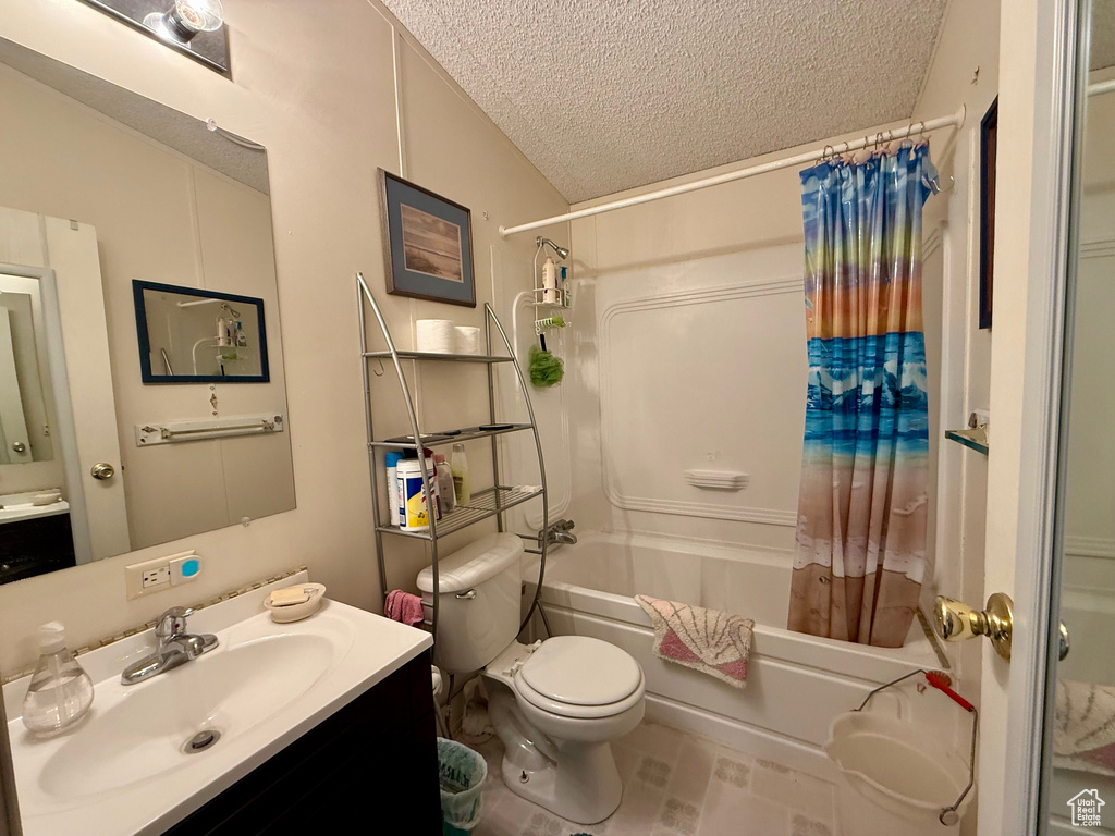 Full bath with vanity, shower / bath combo, toilet, and a textured ceiling