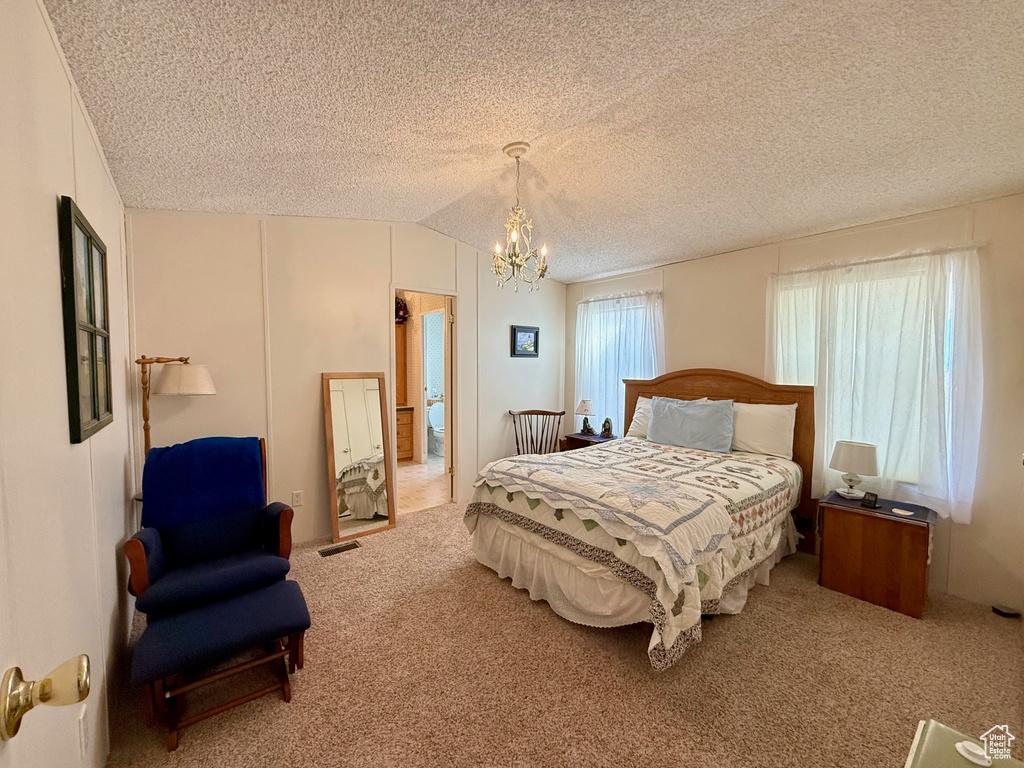 Carpeted bedroom with visible vents, a textured ceiling, a chandelier, and vaulted ceiling
