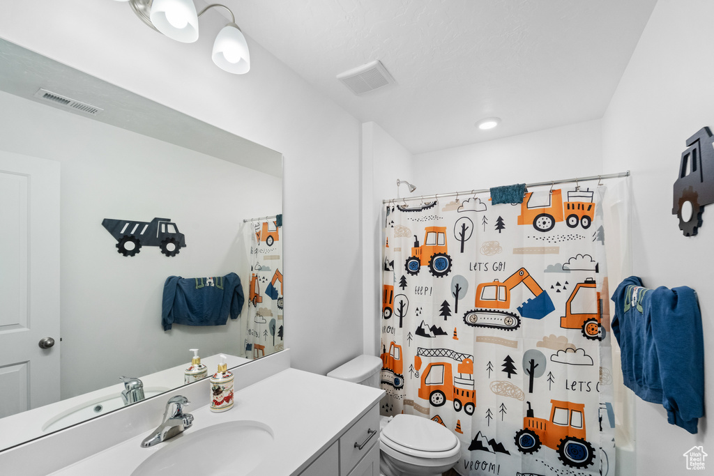 Bathroom with toilet, visible vents, a shower with shower curtain, and vanity