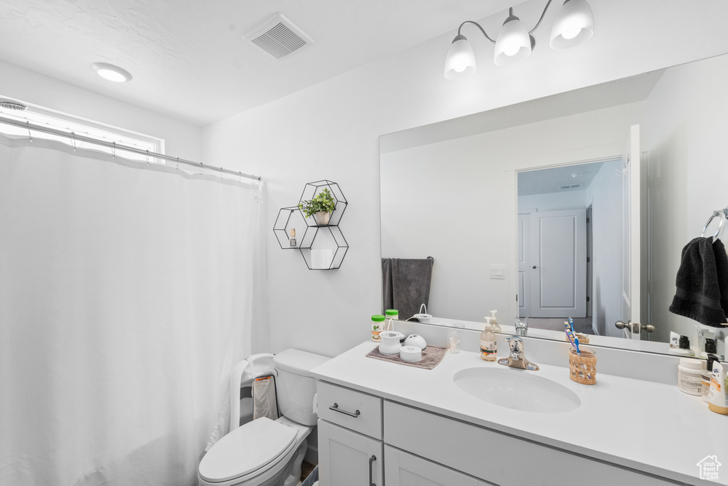 Full bath featuring vanity, a shower with shower curtain, toilet, and visible vents
