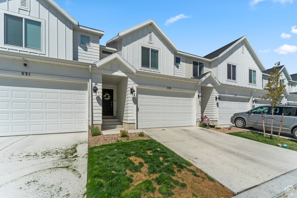 Multi unit property with board and batten siding, driveway, and a garage